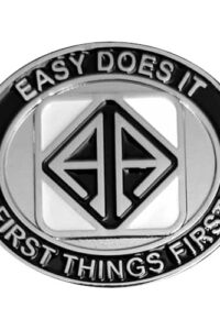 Silver oval medallion with the text "Easy does it" and "First things first" in silver letters inside a black border. In the center, a stylized silver "AA" shaped like a diamond in a black background is set in a white square.